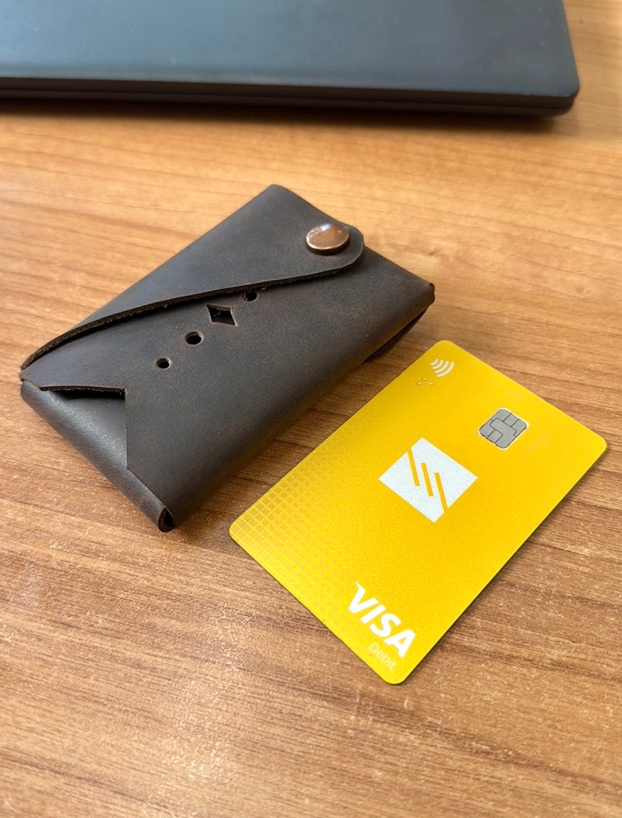 Black wallet and yellow Visa card on a wooden surface