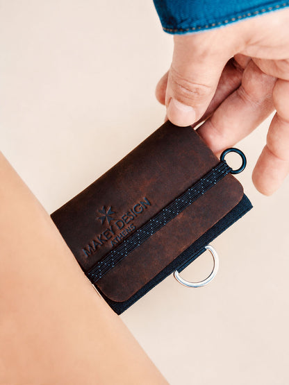 Brown leather key organizer with a ring held by a hand on a beige background
