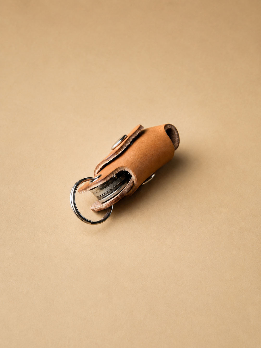 Brown leather key organizer with keys on a beige background
