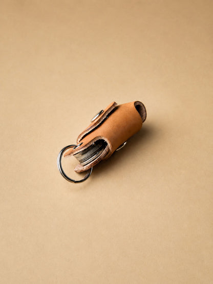 Brown leather key organizer with keys on a beige background