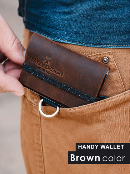 Brown wallet with 'Makey Design' branding being placed into a pocket.