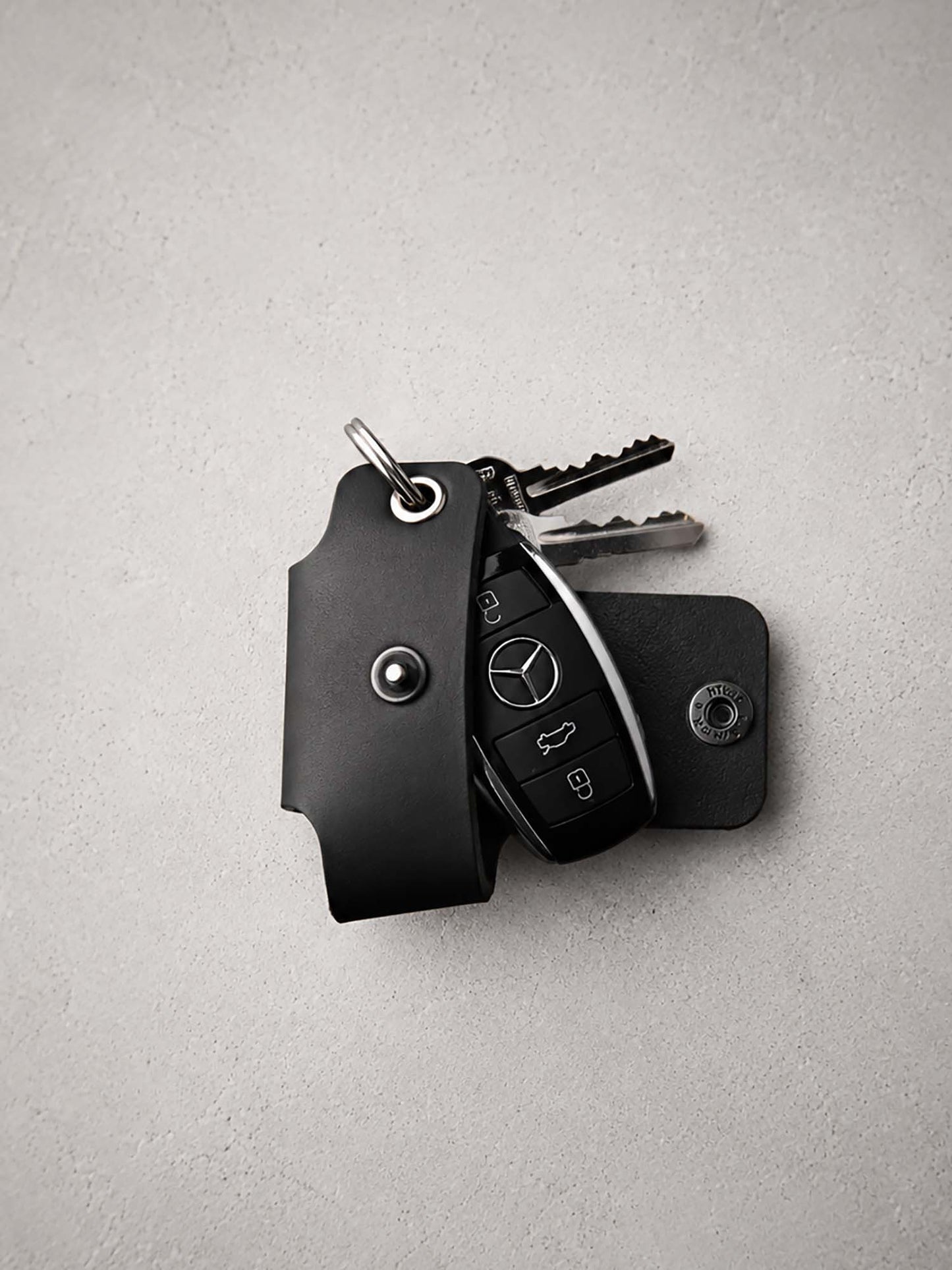 Black key holder with keys on a light gray background