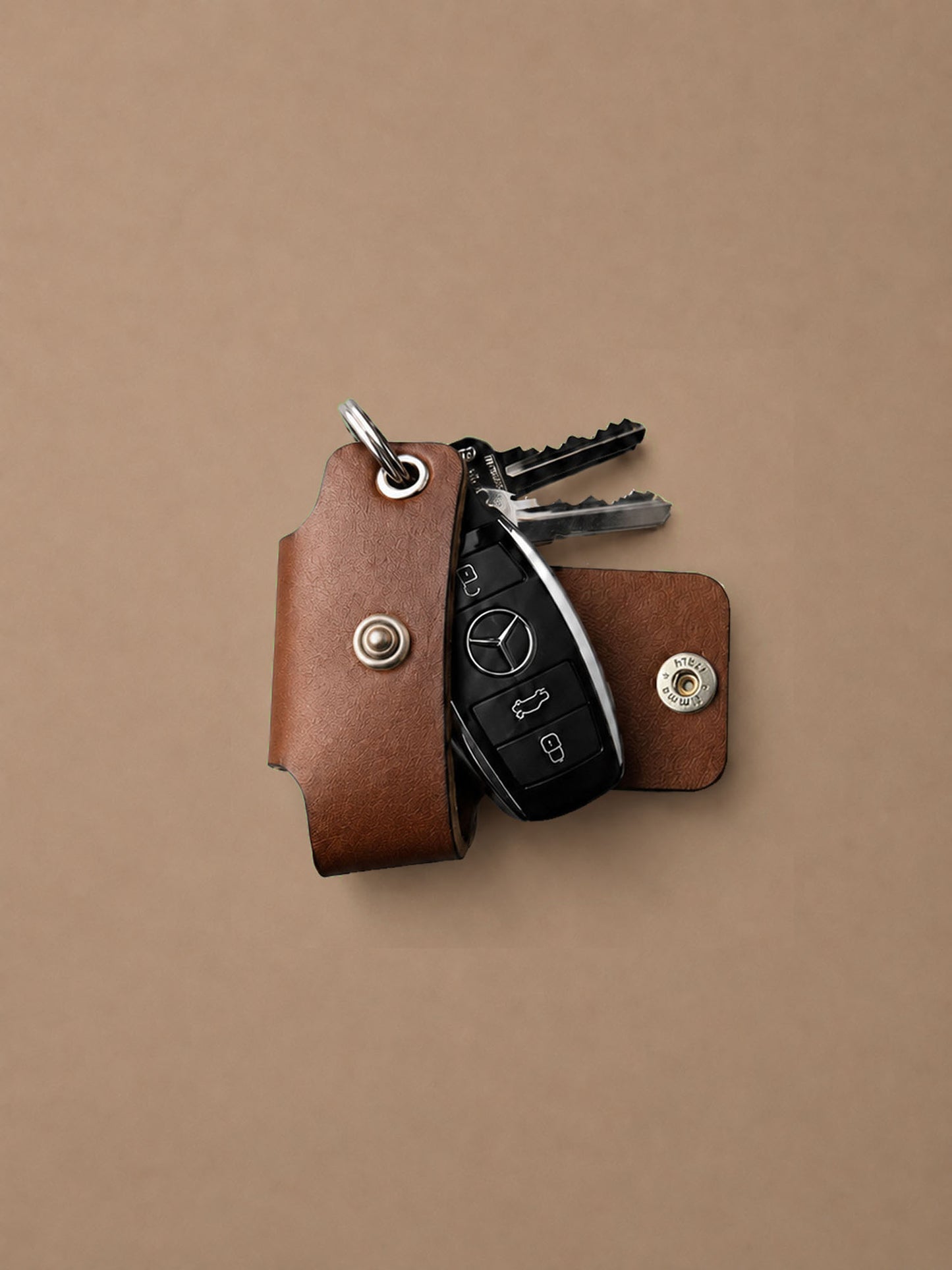 Brown leather key holder with keys on a beige background