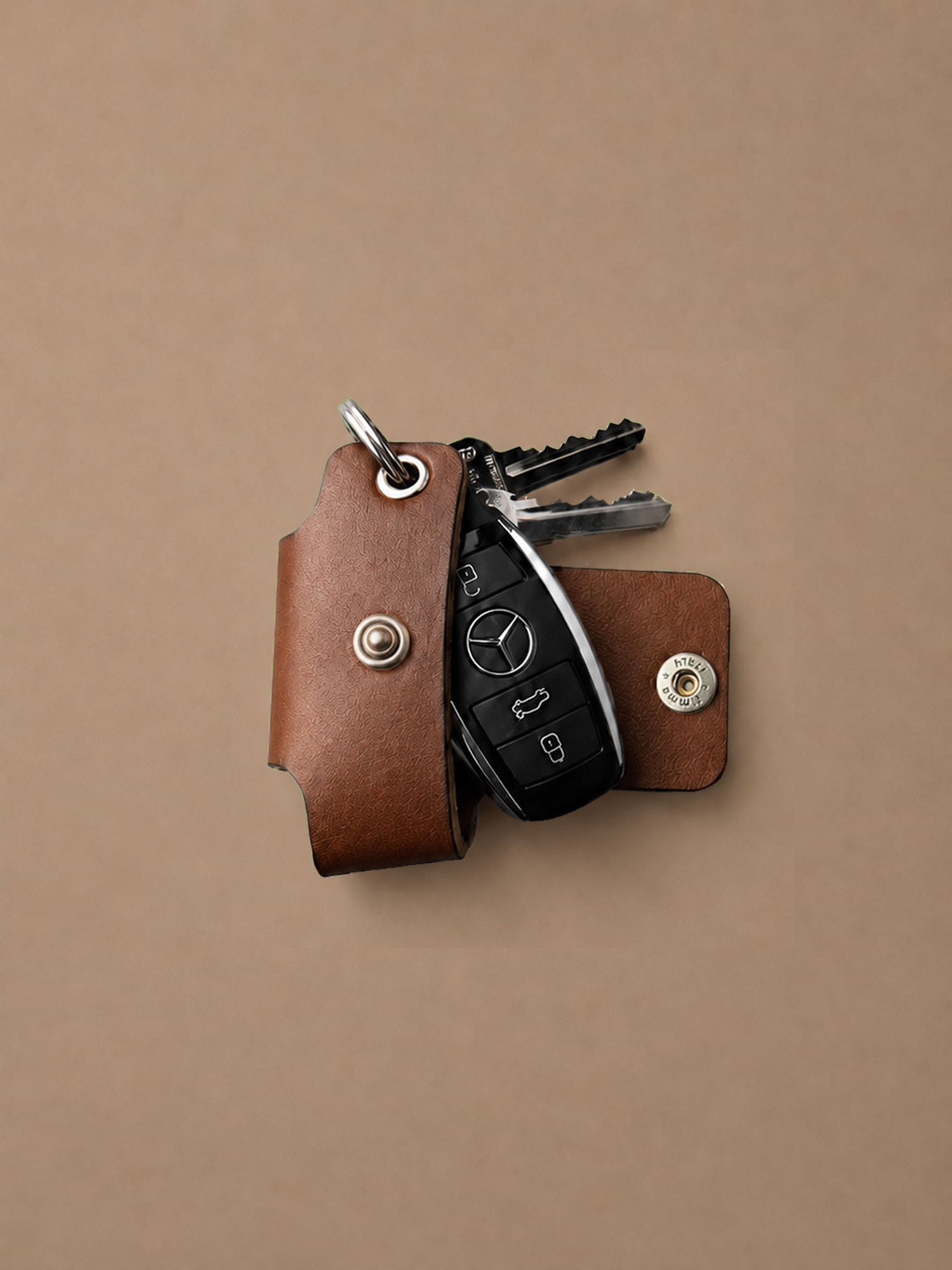 Brown leather key holder with keys on a beige background