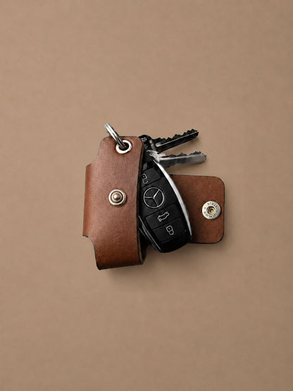 Brown leather key holder with keys on a beige background