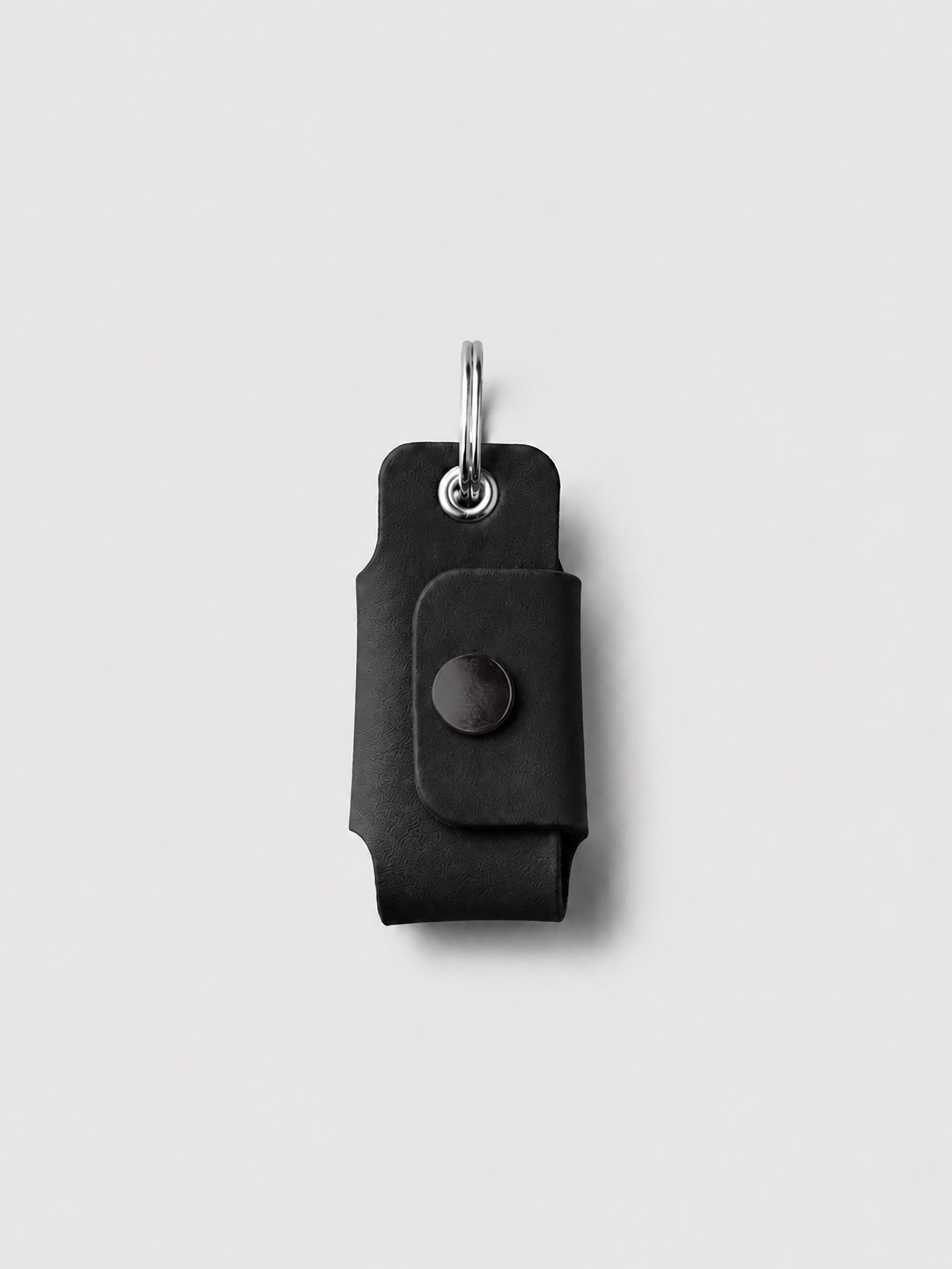 Black key case with a keychain on a light gray background